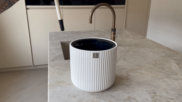 GIF showing Step 1 of the self-watering planter setup: inserting the water level indicator into the planter to begin the assembly process.